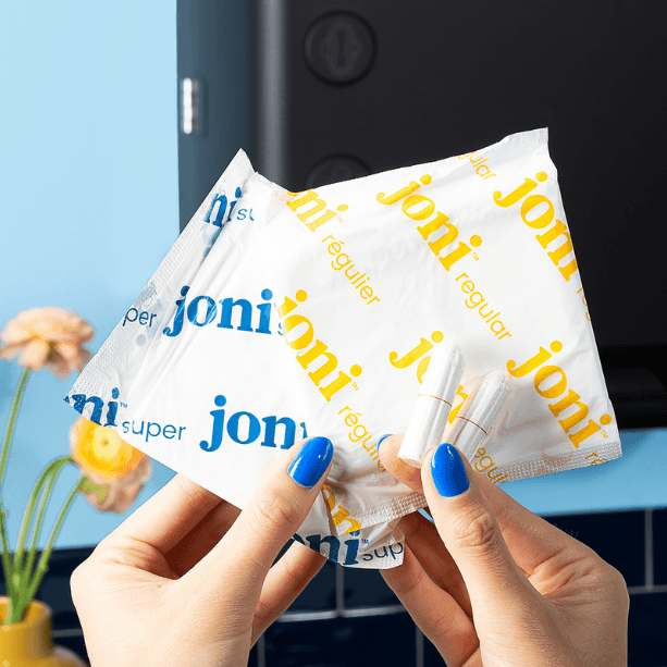 Hands holding multiple 'joni' brand packets with a blurred background