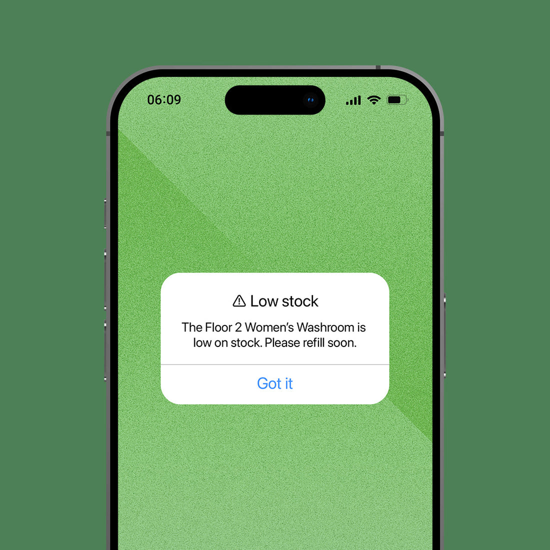 A smartphone centered on a muted green background, displaying a pop-up message that reads 'Low stock' with additional text about the Floor 2 Women's Washroom and a blue 'Got it' link.