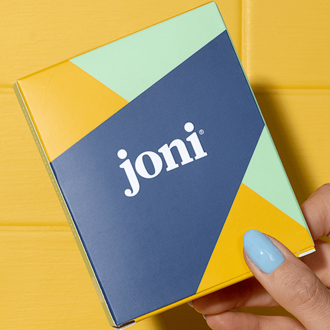 a hand with blue nail polish holds a joni mini box that contains three pads