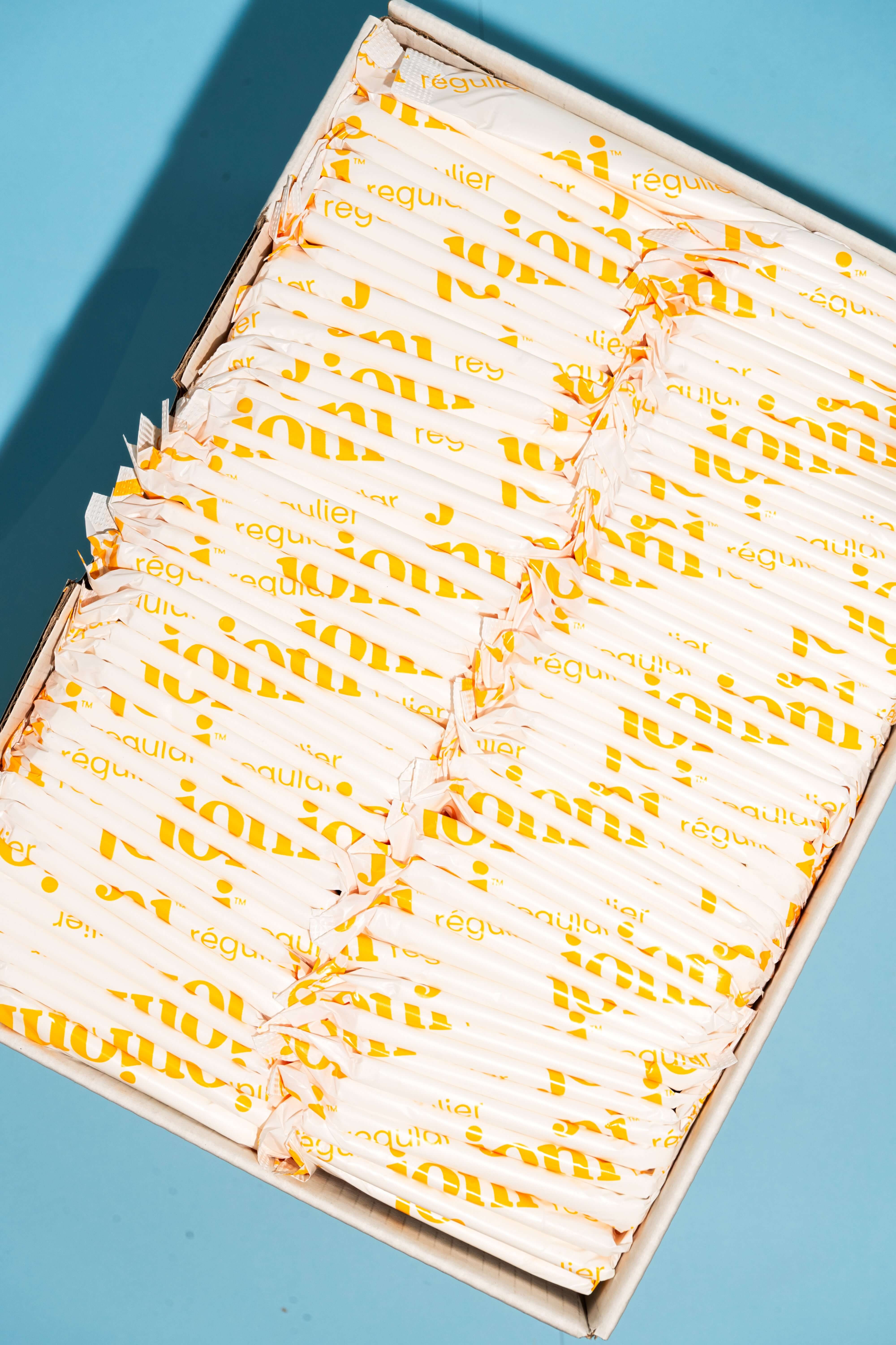Yellow bulk box of joni regular pads with a blue background 