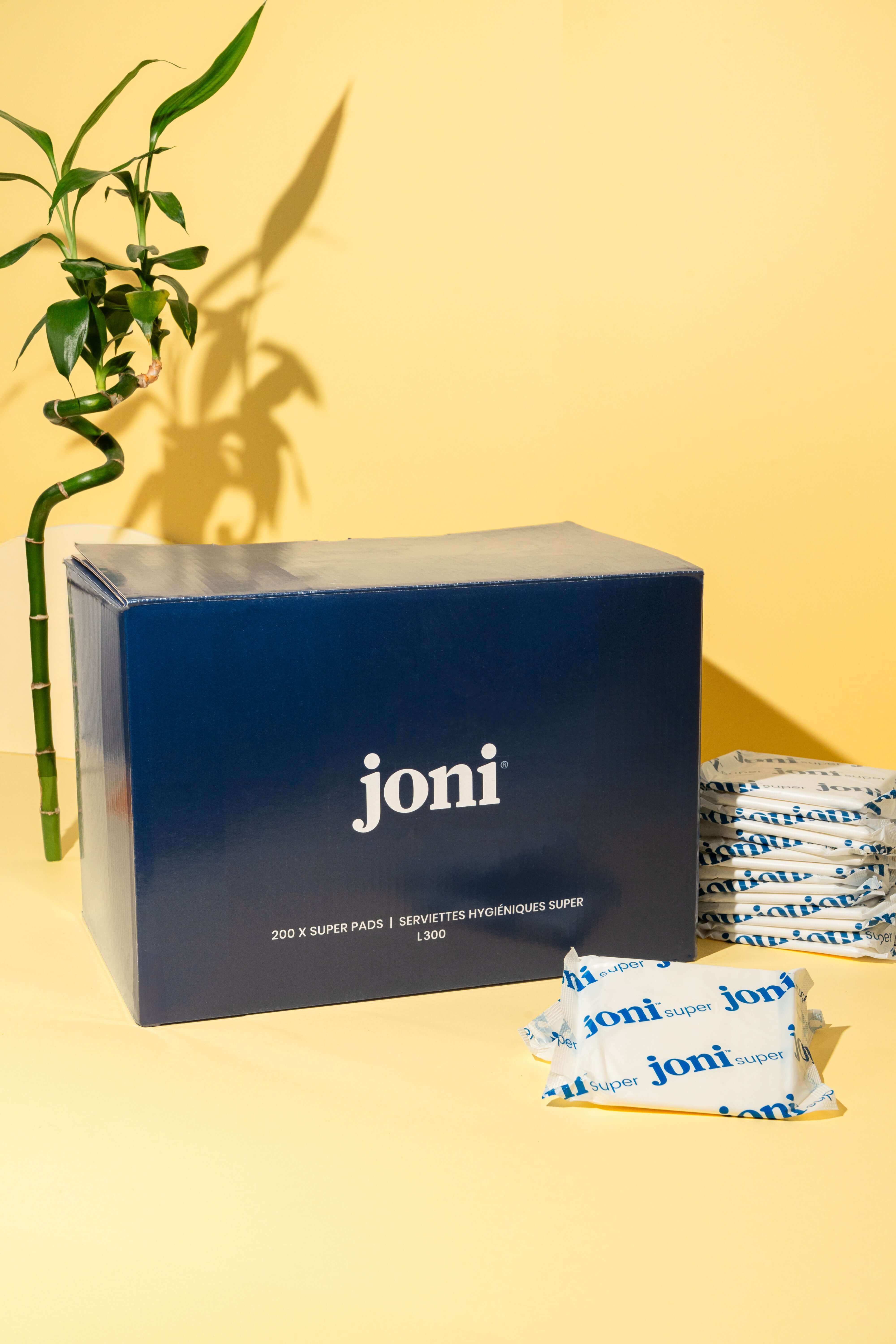 Blue bulk box of joni super pads on a yellow background with bamboo