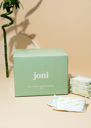 Bulk box of joni bamboo liners beside stacked liners and a bamboo stem