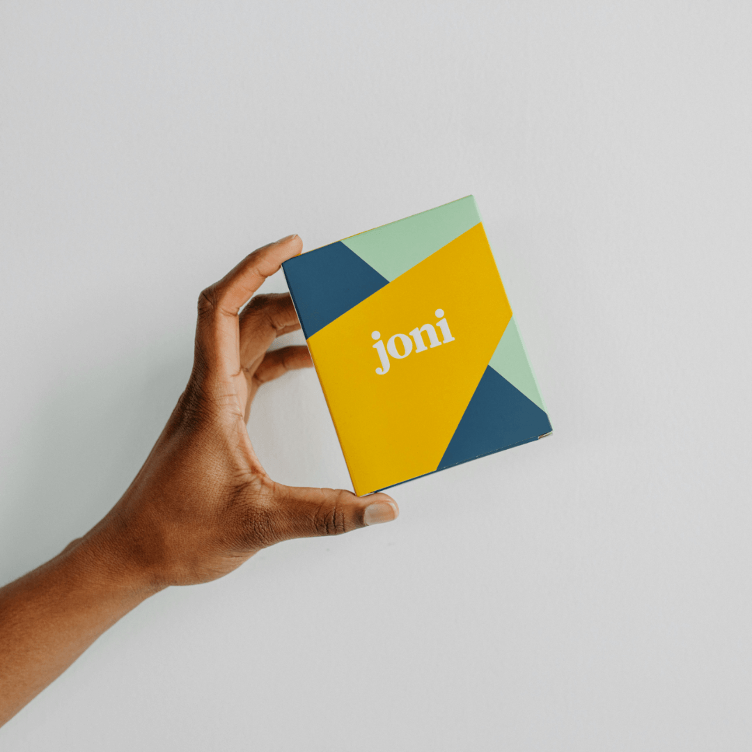 Person holding joni Mini Period Pad Pack in colorful eco-friendly packaging.